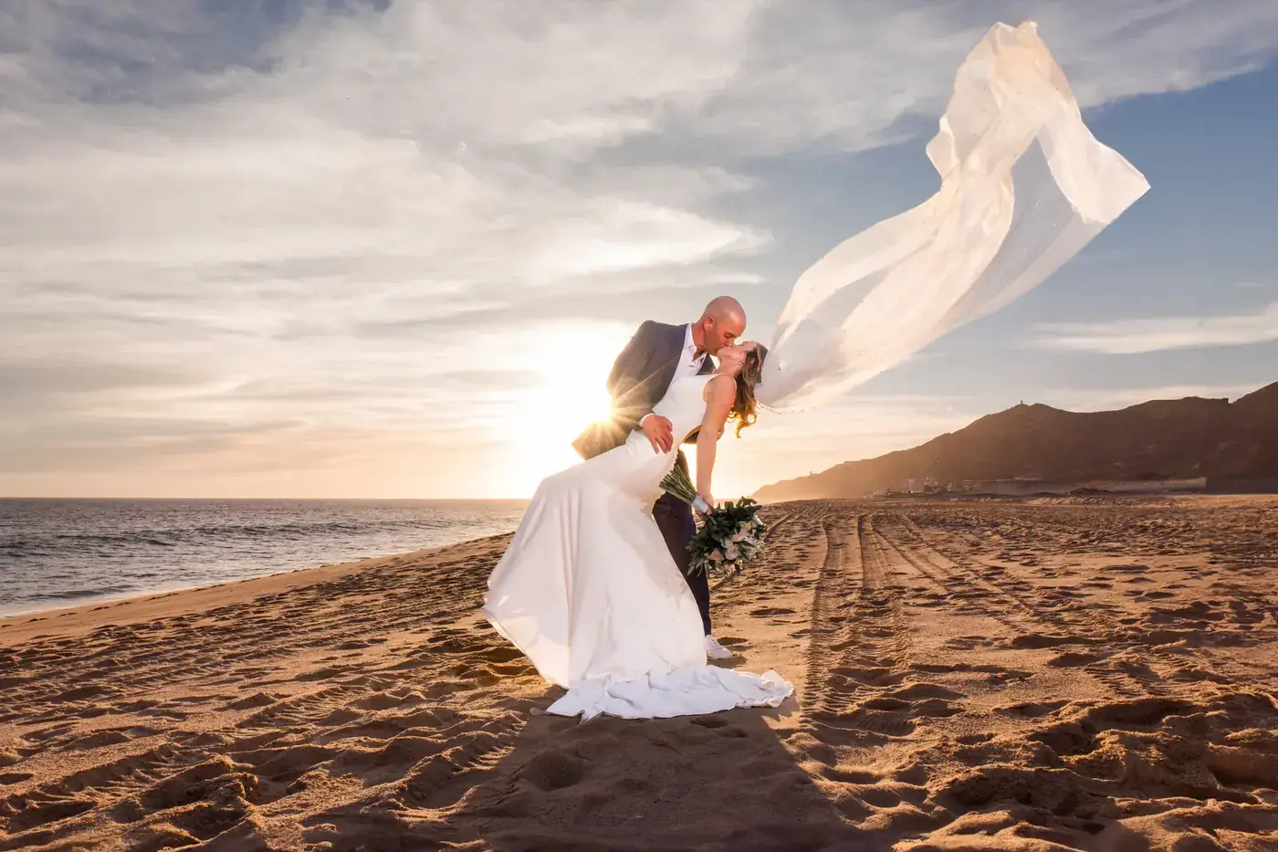 Novios con velo al atardecer, boda en Cabo San Lucas