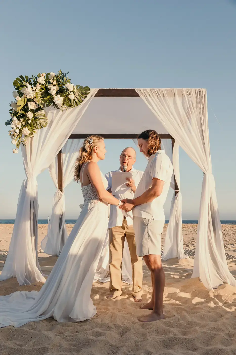 Novios bajo arco floral en la playa de Cabo San Lucas