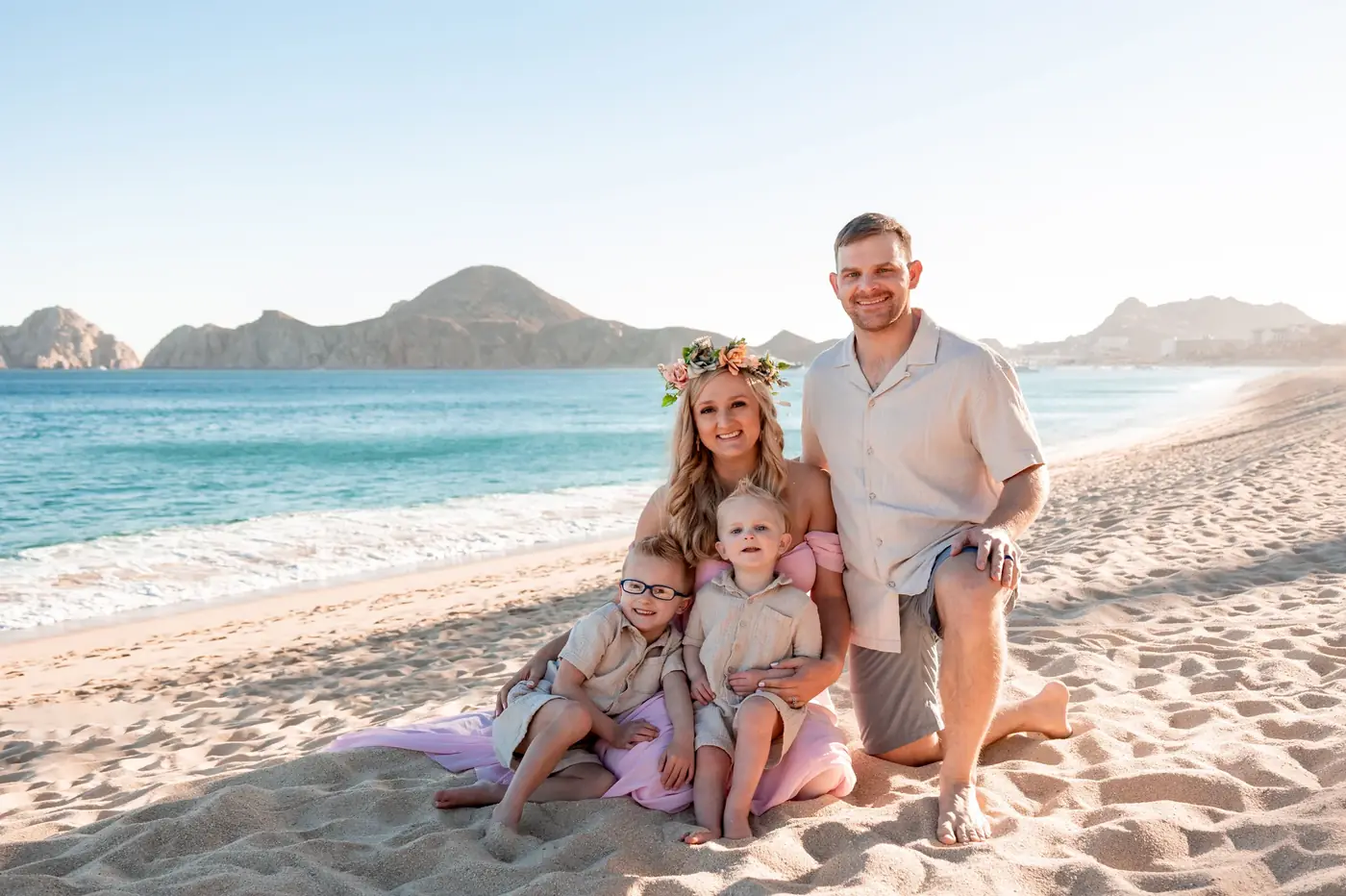 Familia con coronas de flores en la playa a la hora dorada