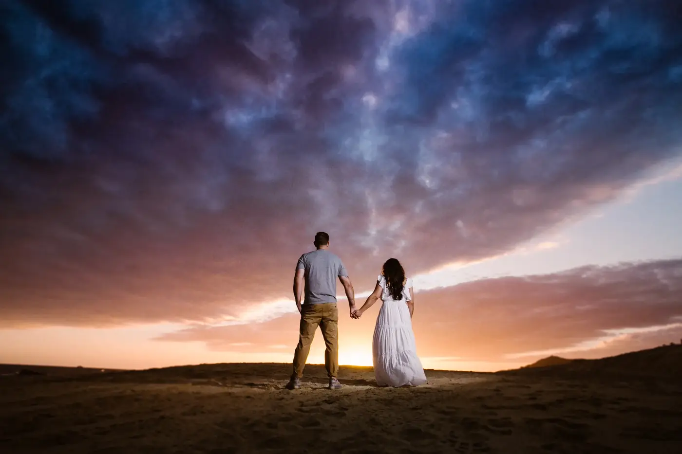 Pareja tomada de la mano al atardecer, sesión de compromiso