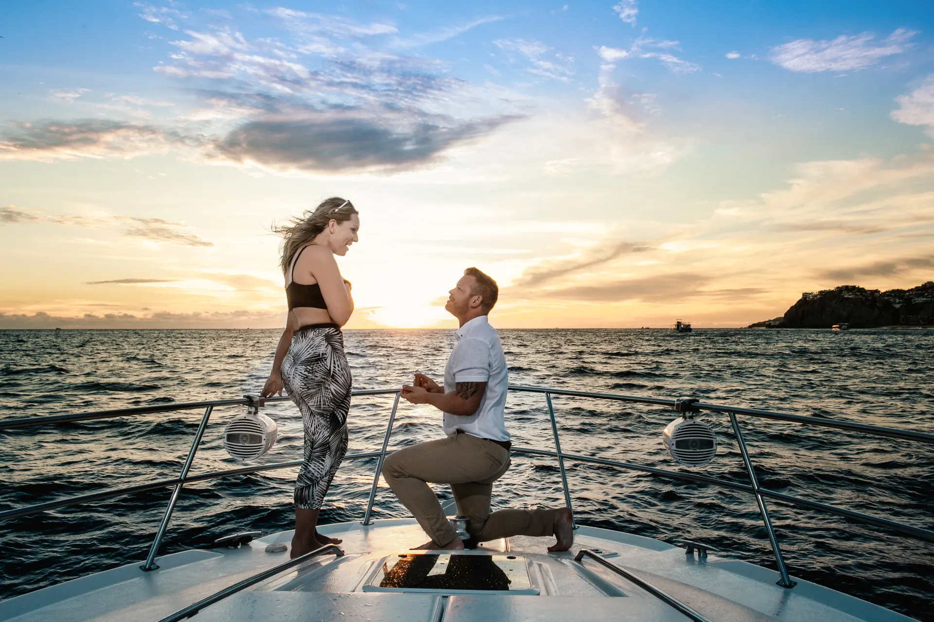 The proposal — a man on one knee on the bow of a yacht at sunset in Cabo San Lucas