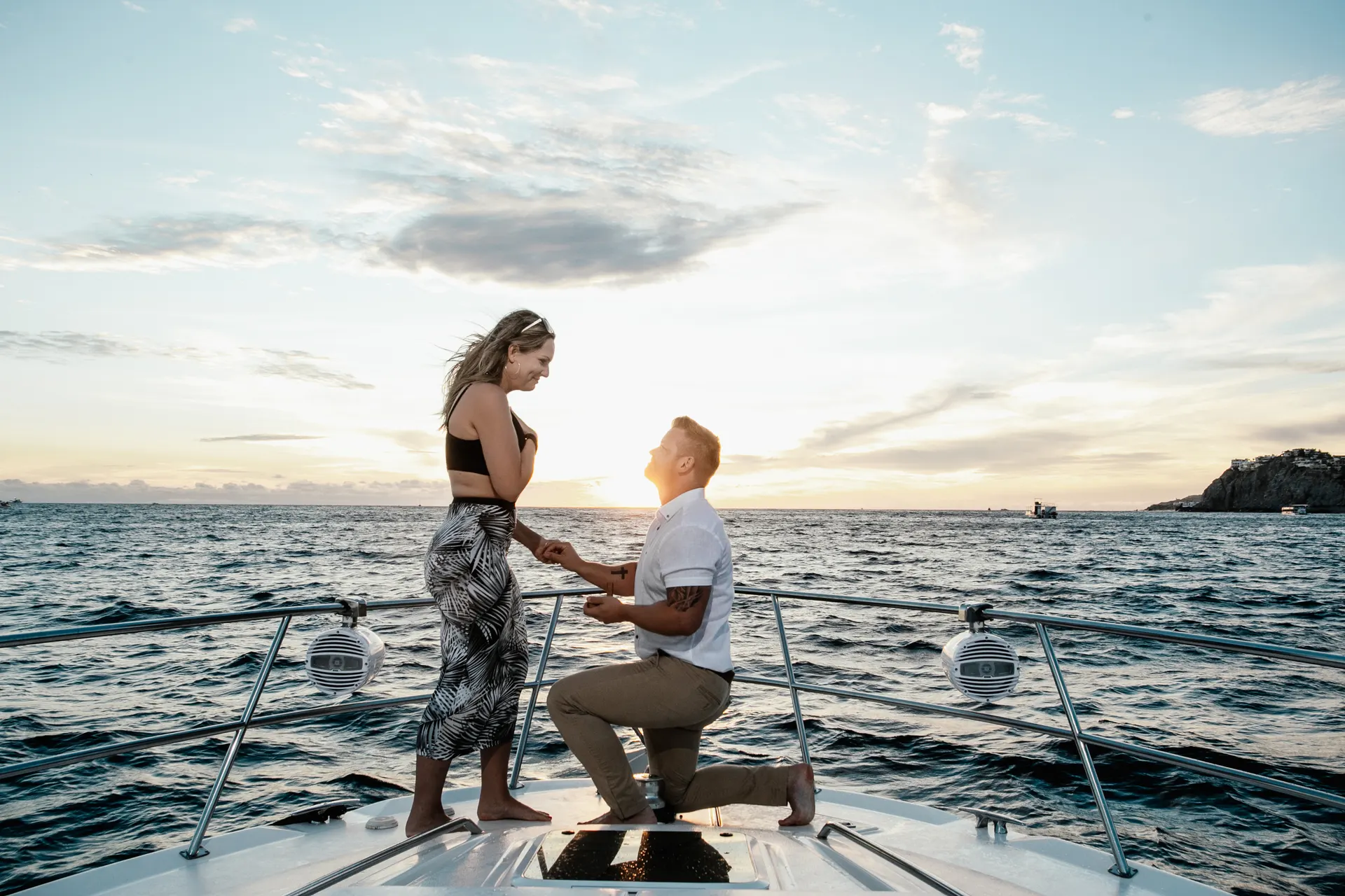The moment she says yes — a couple at sunset on a yacht bow during a Cabo San Lucas proposal